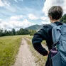 Garçon adolescent, de dos, face à un chemin en randonnée, avec son sac à dos.